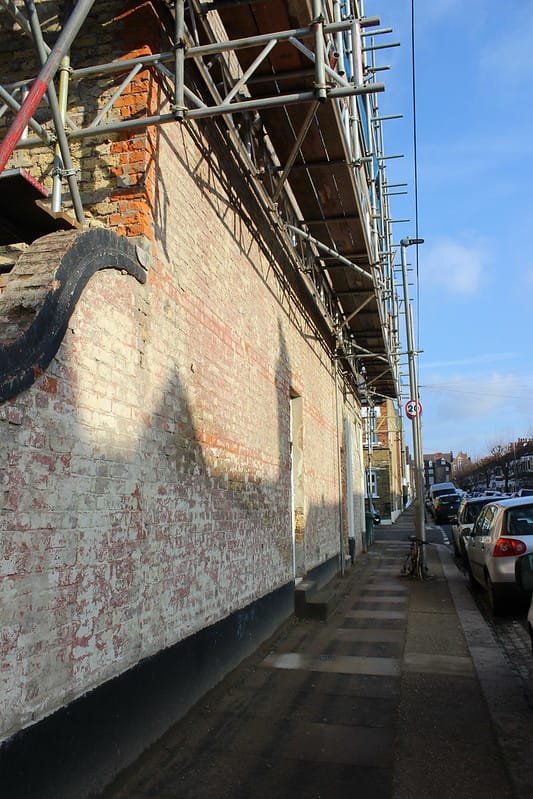 A wall in disrepair with scaffold around